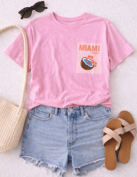 Look été femme avec t-shirt rose Miami beach, short en jean et sac en paille